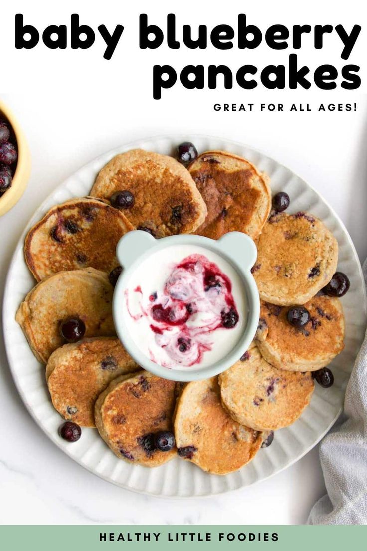 blueberry pancakes on a plate with yogurt and berries in the bowl next to them