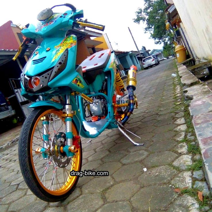 a blue and yellow motorcycle parked on the side of a road next to a building