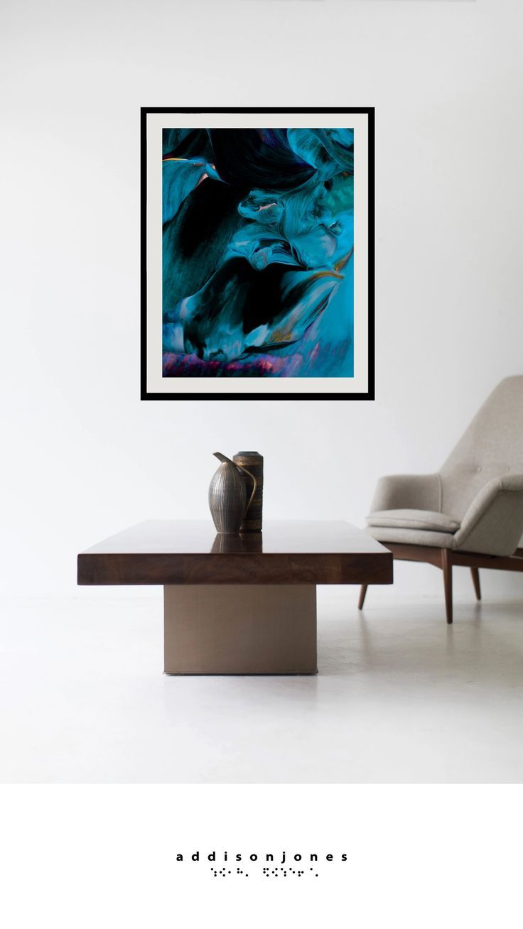 an abstract painting hangs above a modern coffee table