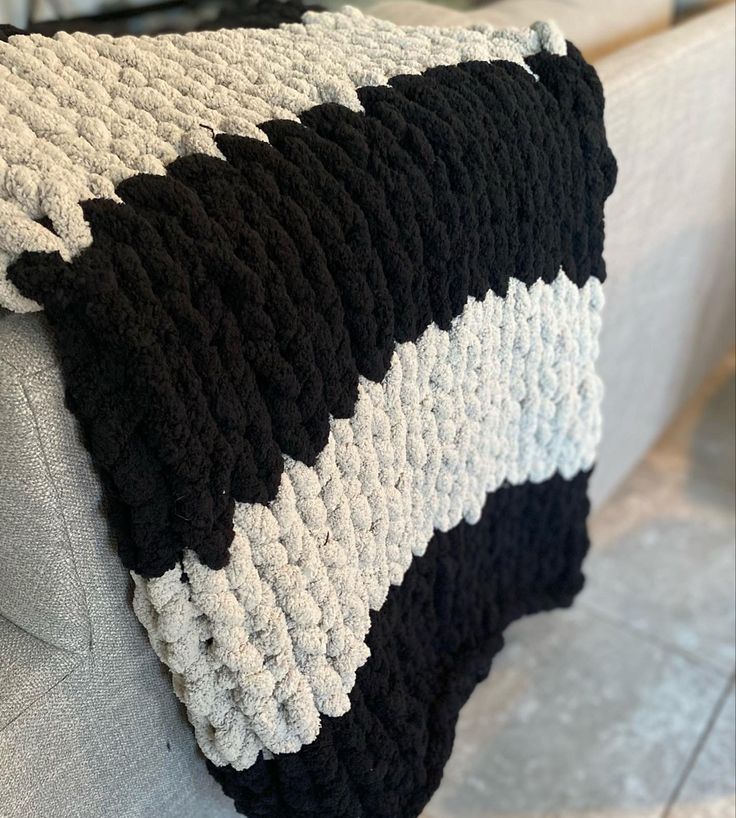 a black and white crocheted blanket sitting on top of a couch