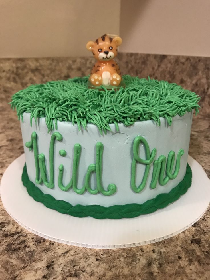 a cake with green frosting and a teddy bear on top