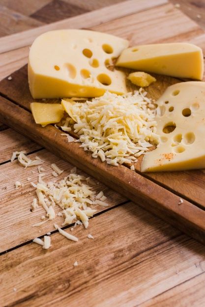 several pieces of cheese are on a cutting board with grated parmesan cheese