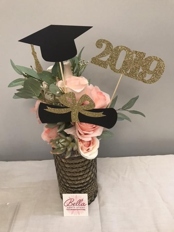 a graduation centerpiece with pink flowers and greenery