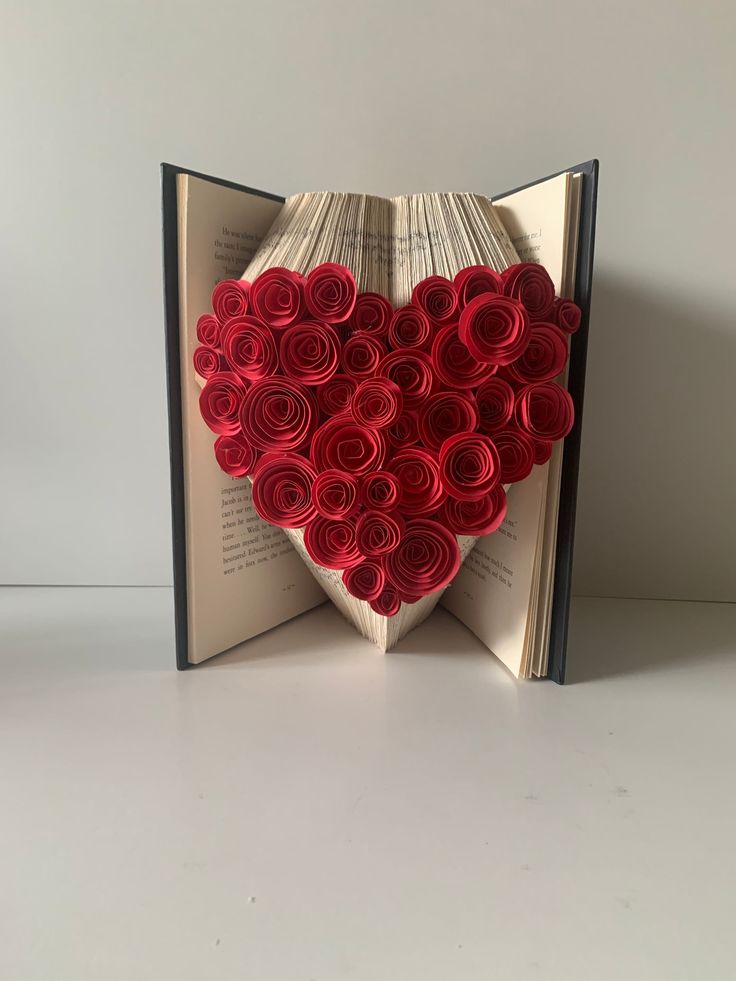 an open book with paper roses in the shape of a heart