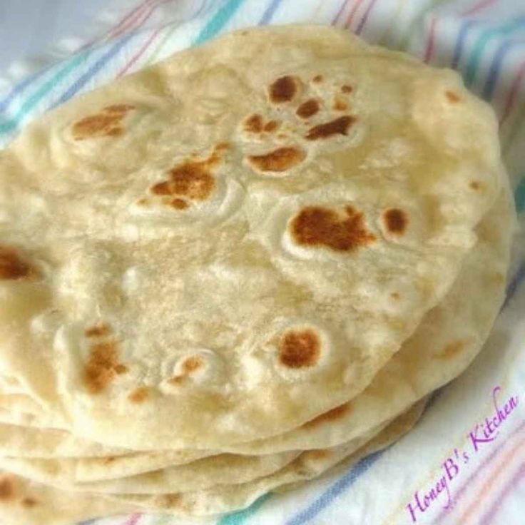 three flat breads sitting on top of a striped table cloth next to each other