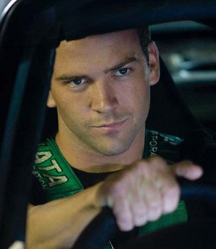 a man sitting in a car with his hand on the steering wheel