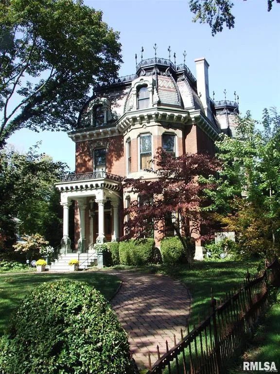 a large brick house sitting in the middle of a lush green park with lots of trees