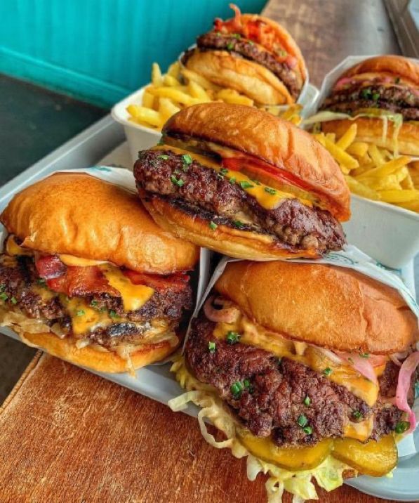 three cheeseburgers and french fries on a tray