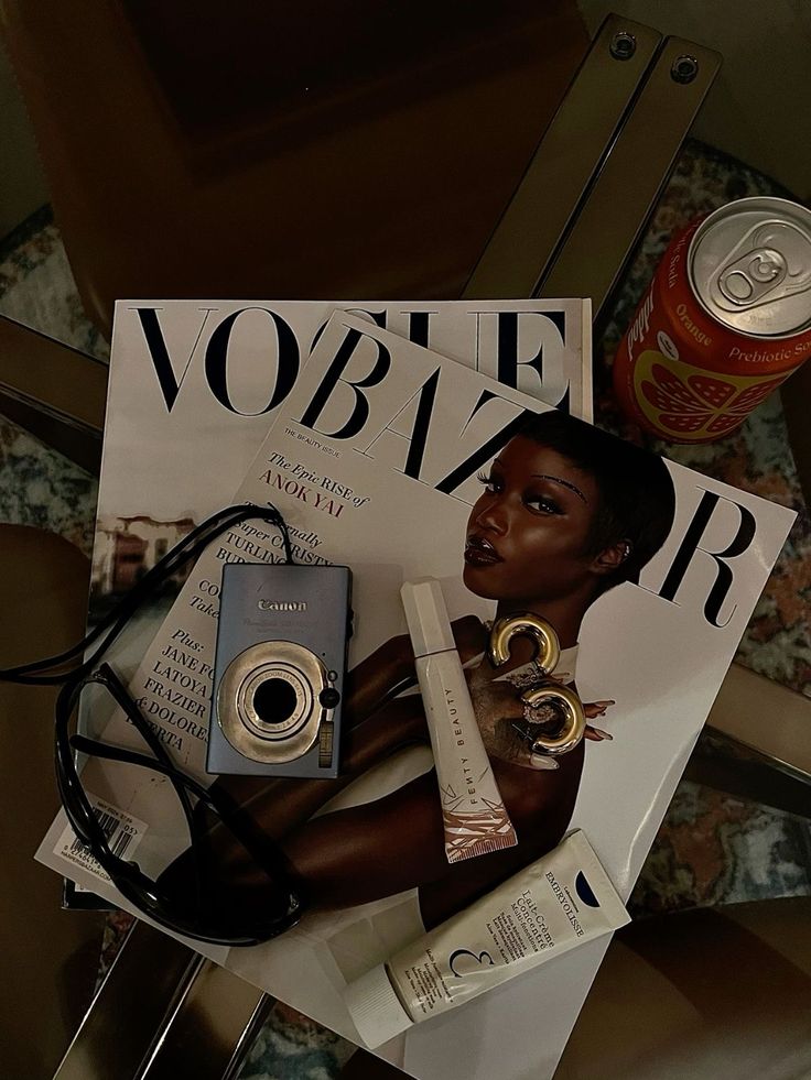 a magazine with an image of a woman holding a camera on top of it next to a can of soda