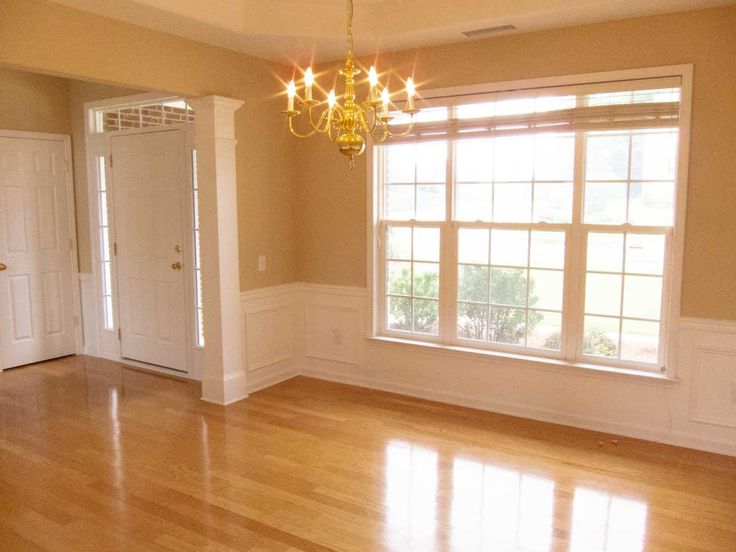 an empty room with hard wood floors and chandelier