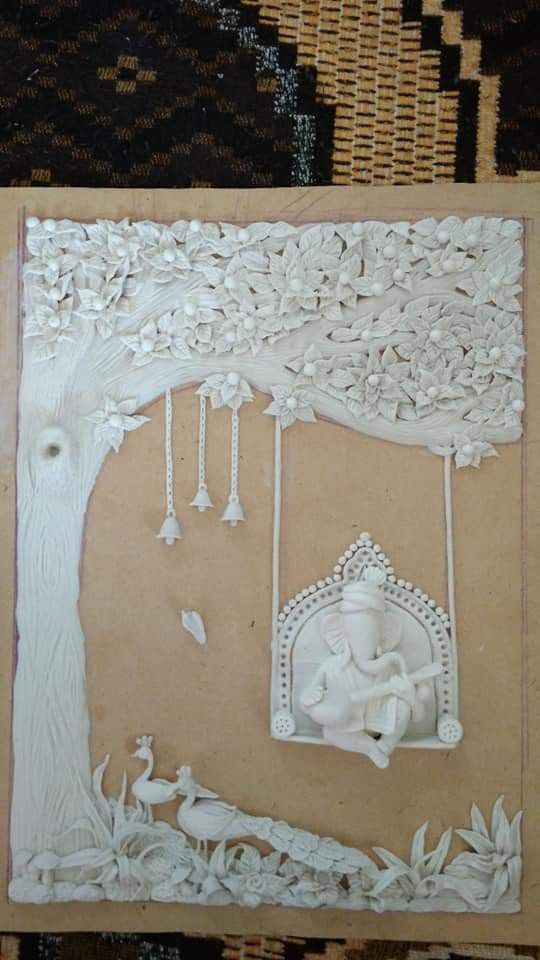 an intricately carved paper art depicting a tree and swing