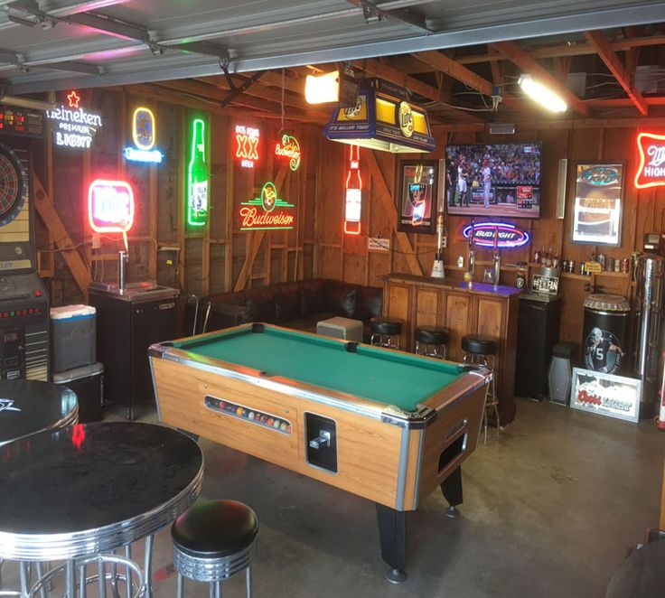 a man cave with pool tables and neon signs