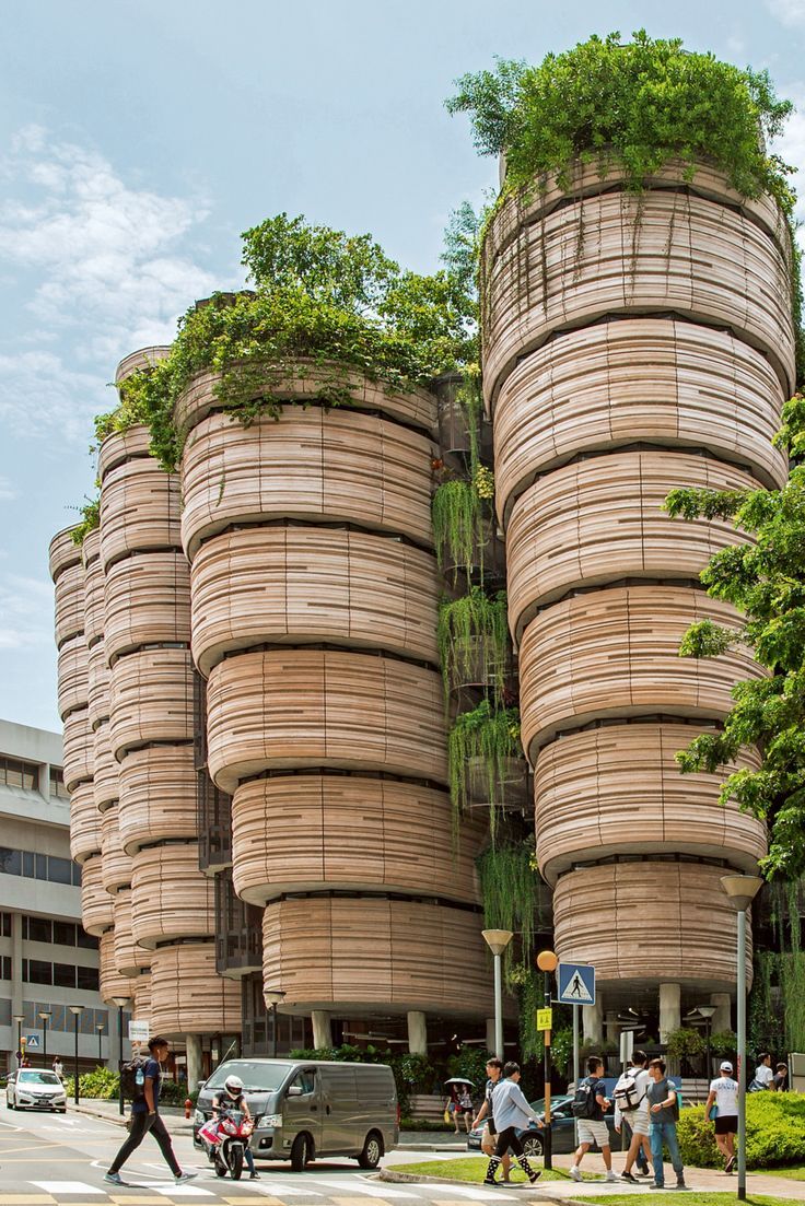 people crossing the street in front of an unusual building with trees growing out of it