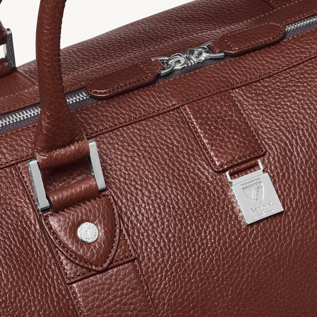 Luxury Cognac Weekender Bag For Everyday, Classic Cognac Business Duffle Bag, Luxury Cognac Duffle Bag For Travel, Luxury Brown Weekender Bag For Business, Luxury Cognac Weekender Bag With Smooth Grain, Classic Business Travel Bag In Textured Leather, Designer Leather Luggage With Sleeve, Designer Leather Weekender Bag For Business, Luxury Cognac Smooth Grain Weekender Bag