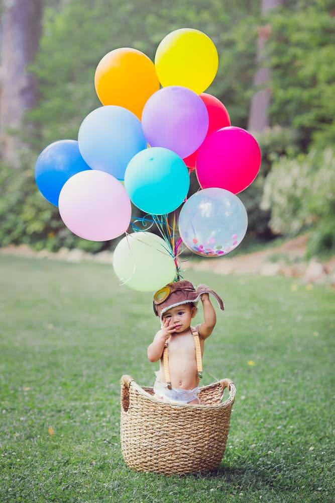 a baby sitting in a basket with balloons