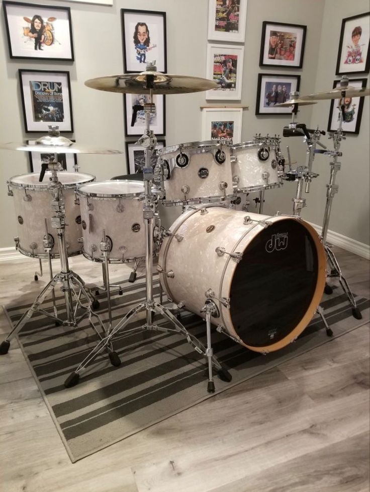 a drum set sitting on top of a hard wood floor next to framed pictures in a room