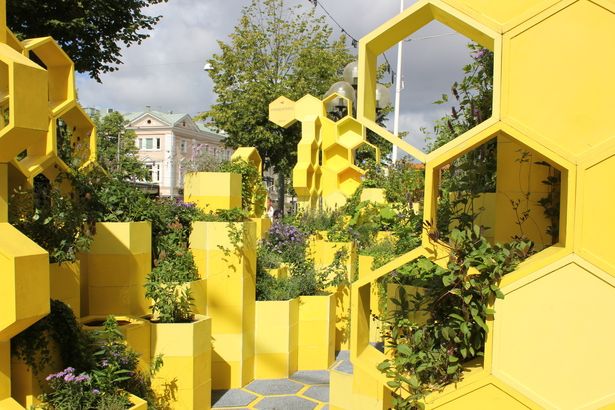 a yellow building with many plants growing on the sides and in the middle of it