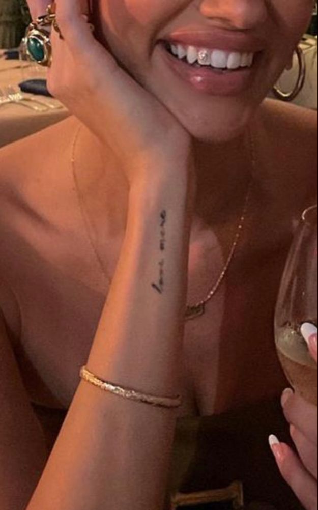 a woman with a tattoo on her arm holding a wine glass and looking at the camera