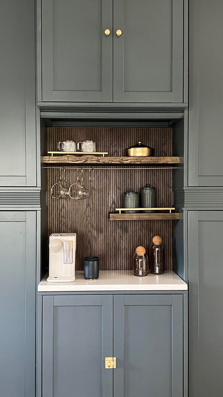 a kitchen with gray cabinets and white counter tops, gold pulls on the cupboards