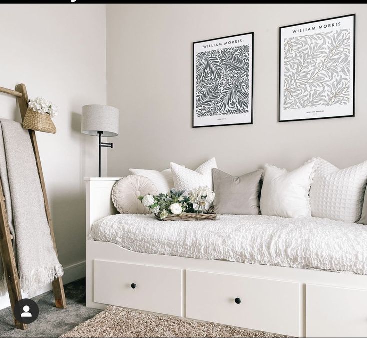 a white day bed sitting in a bedroom next to two pictures on the wall