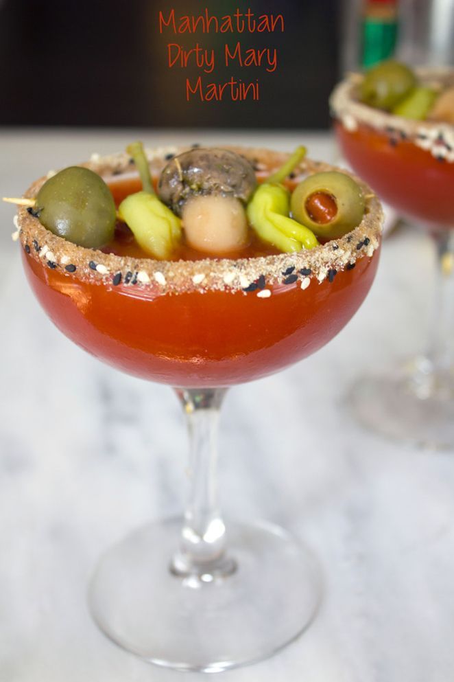 two martinis with olives, tomatoes and other toppings on the rim are ready to be served