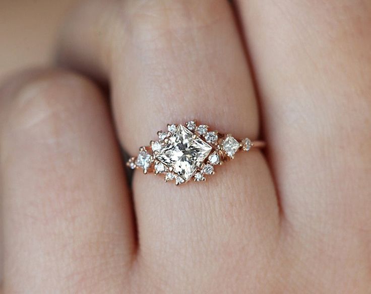 a woman's hand with a diamond ring on top of her finger and an engagement band