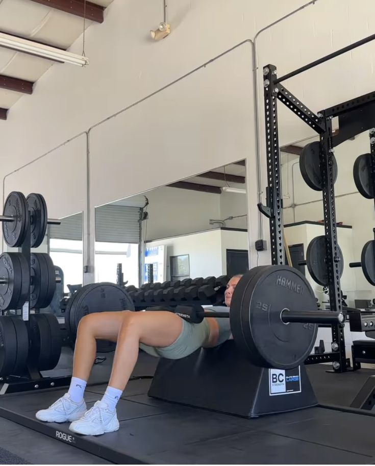 a woman is doing squats on a bench in front of a gym equipment rack