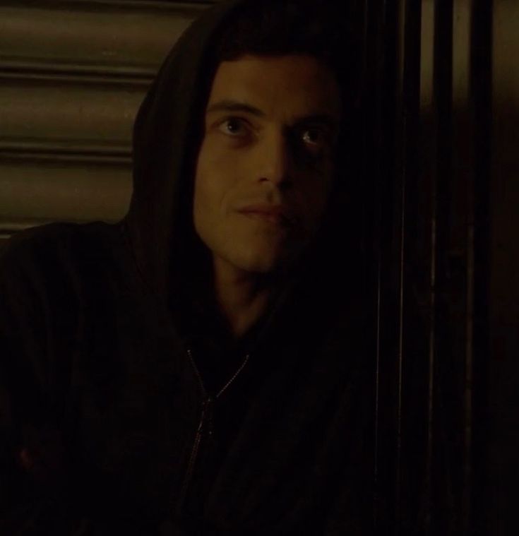 a man in a black hoodie is staring into the distance with his eyes wide open