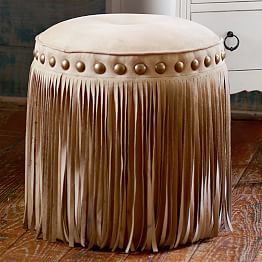 a stool with fringes on it in front of a dresser