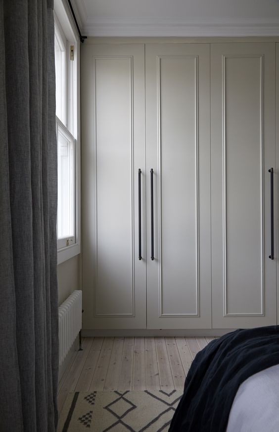 a bedroom with white cupboards and curtains