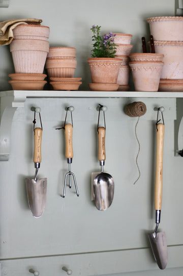 pots and gardening utensils hanging on a shelf