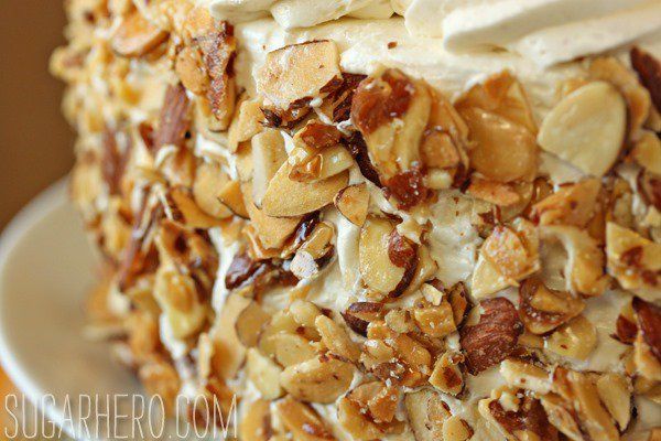 a close up of a cake on a plate with nuts and whipped cream frosting