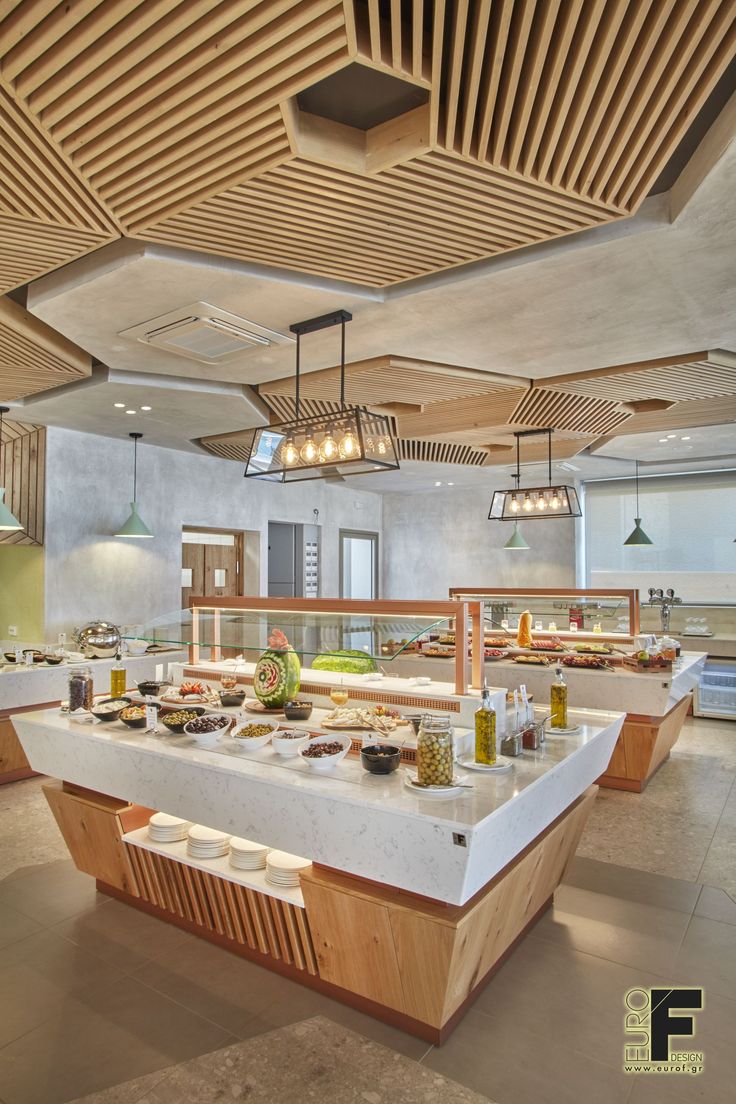 an open kitchen with lots of food on the counter and lights hanging from the ceiling