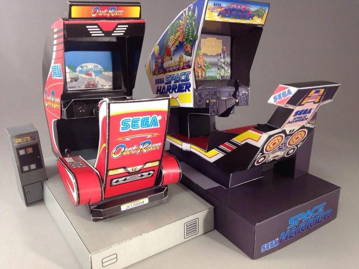 three arcade machines sitting next to each other on top of a table in front of a gray background