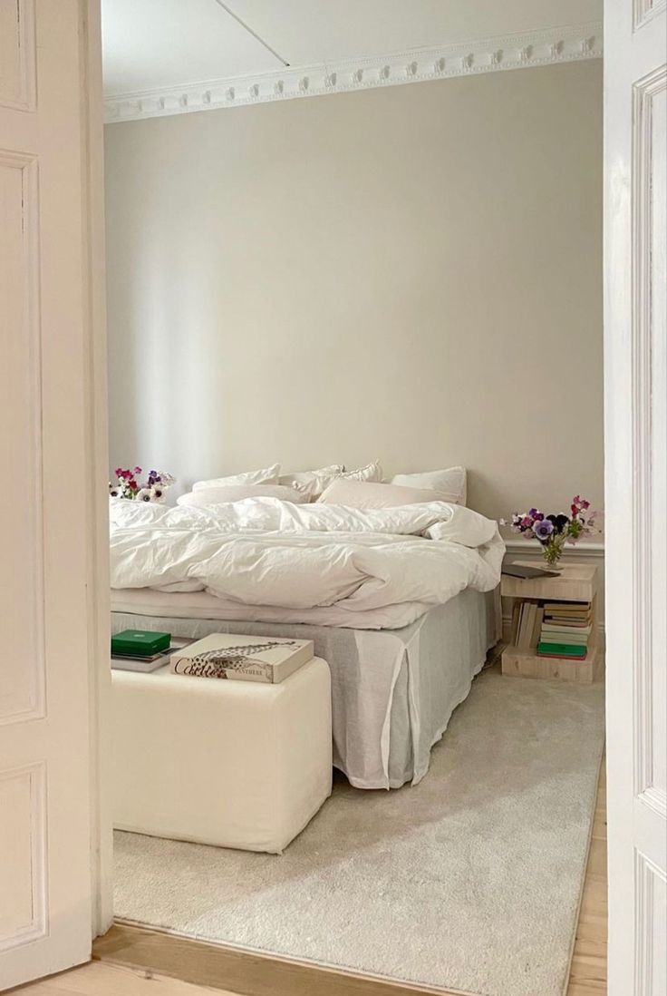 a white bed sitting in the middle of a bedroom next to a doorway with an open door