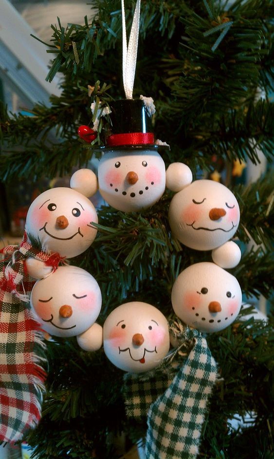 an ornament hanging from a christmas tree decorated with snowmen and plaid fabric