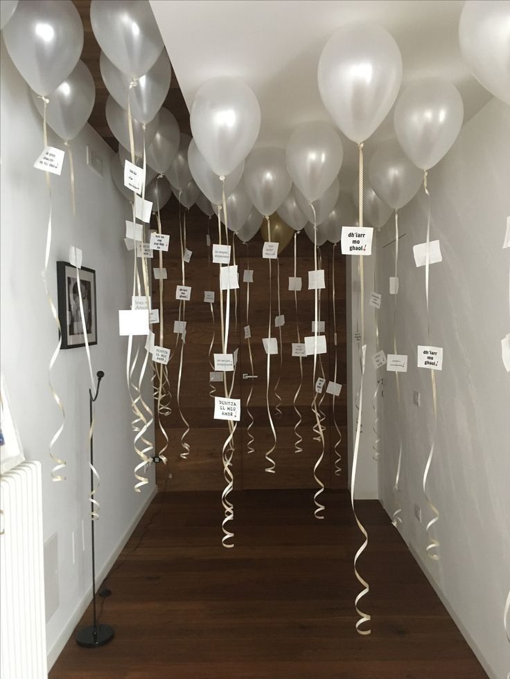 balloons and streamers hang from the ceiling in an empty room with wooden flooring