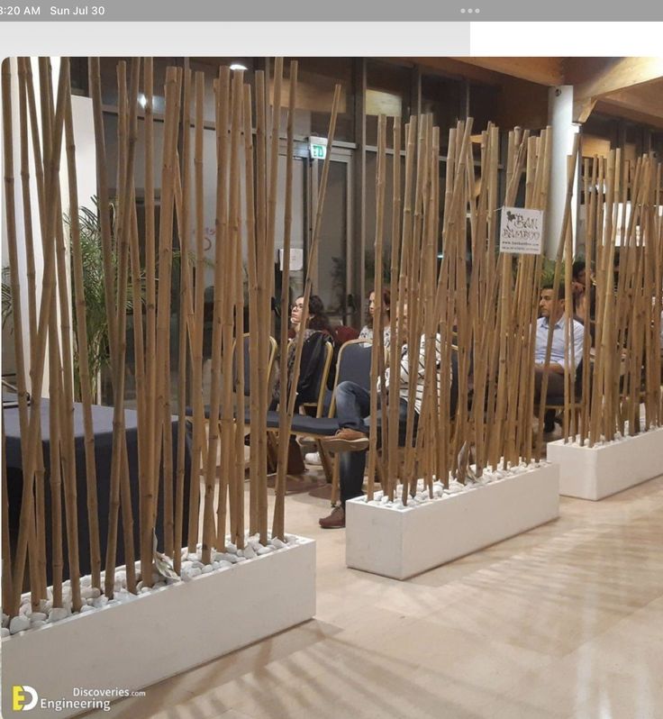 several people are sitting in chairs with wooden poles on the wall and behind them is a display of bamboo sticks