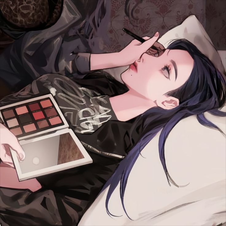 a woman laying on top of a bed holding a palette and eyeliners in her hand