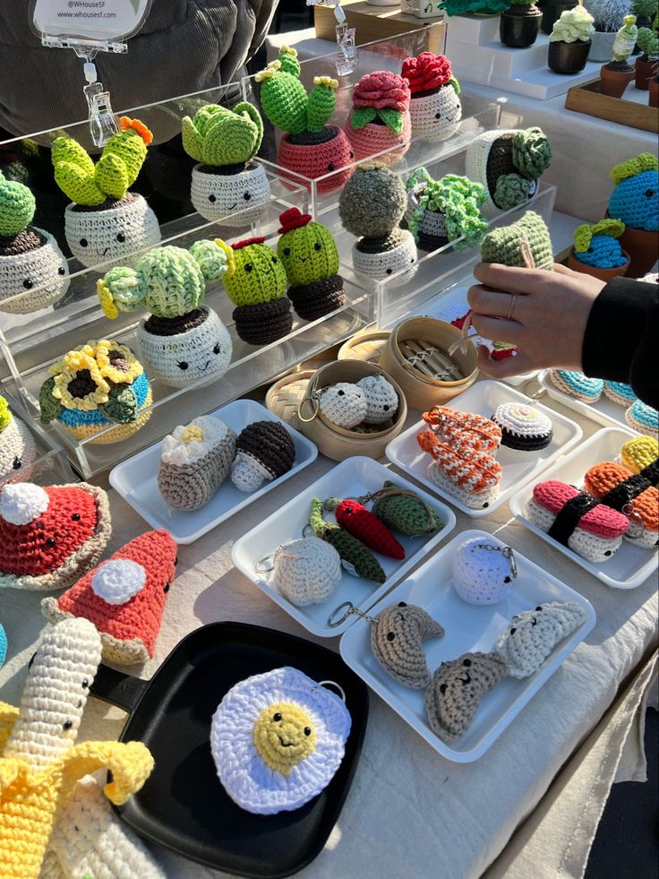 there are many crocheted items on display at this market table, including cupcakes and muffins