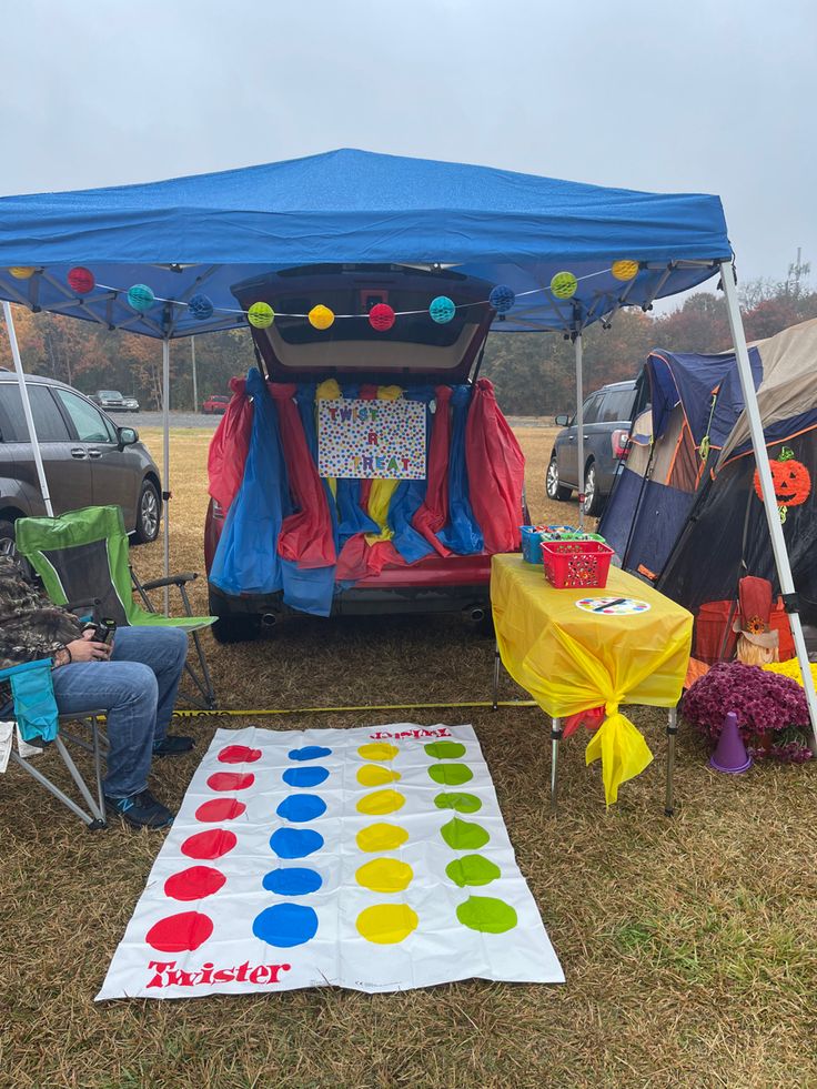 a group of people sitting under a tent next to a giant dot board on the ground