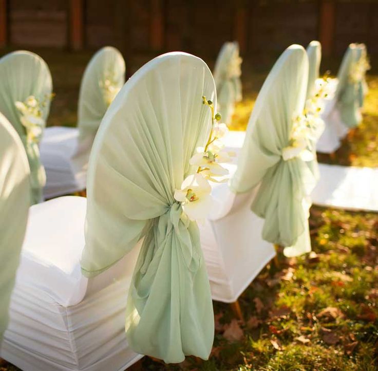 rows of white chairs with green sashes and flowers on them