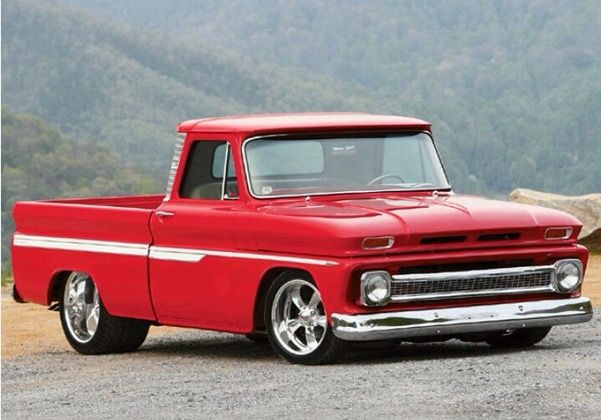 an old red pickup truck parked on the side of a road