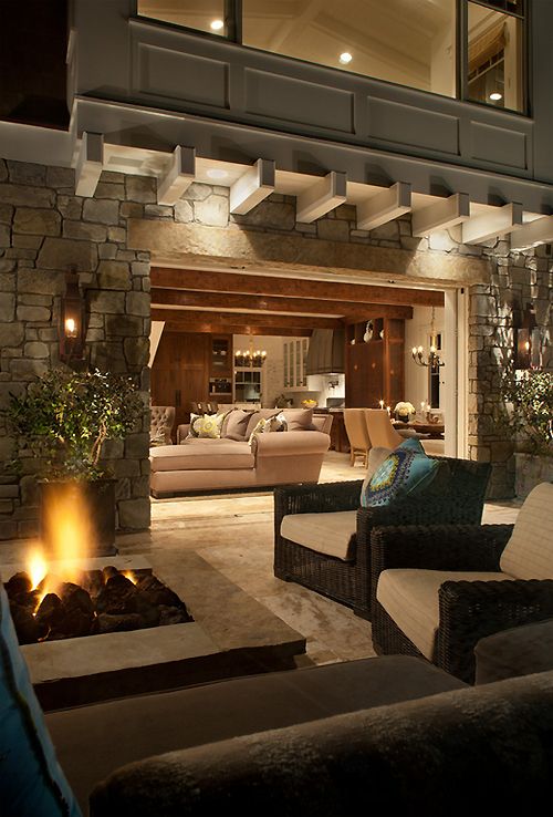 a living room filled with lots of furniture next to a fire place in front of a stone wall