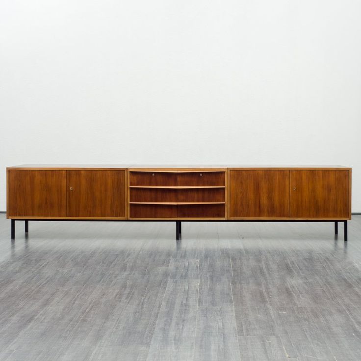 a wooden cabinet sitting on top of a hard wood floor next to a white wall