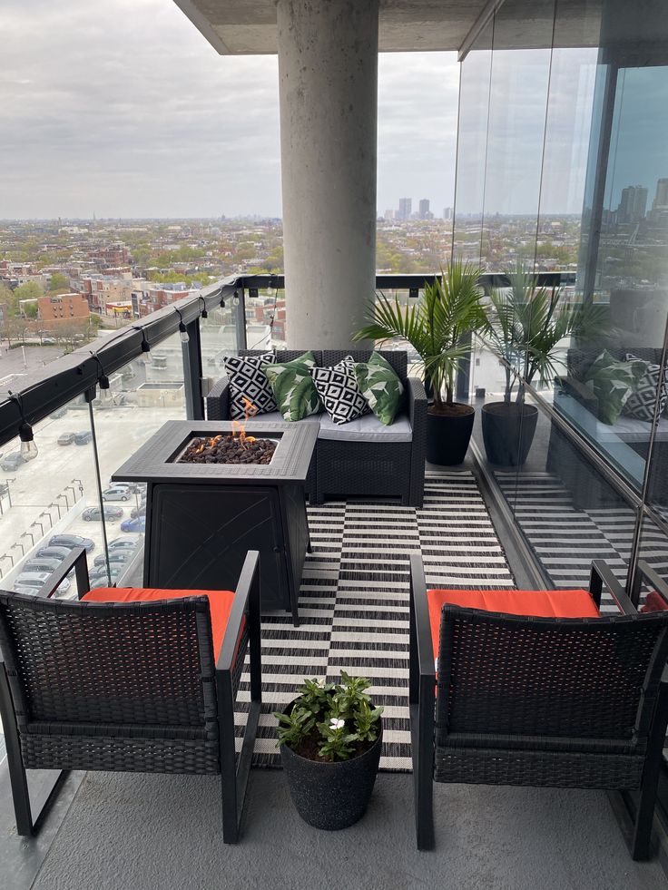 an outdoor seating area with potted plants on the balcony overlooking a cityscape