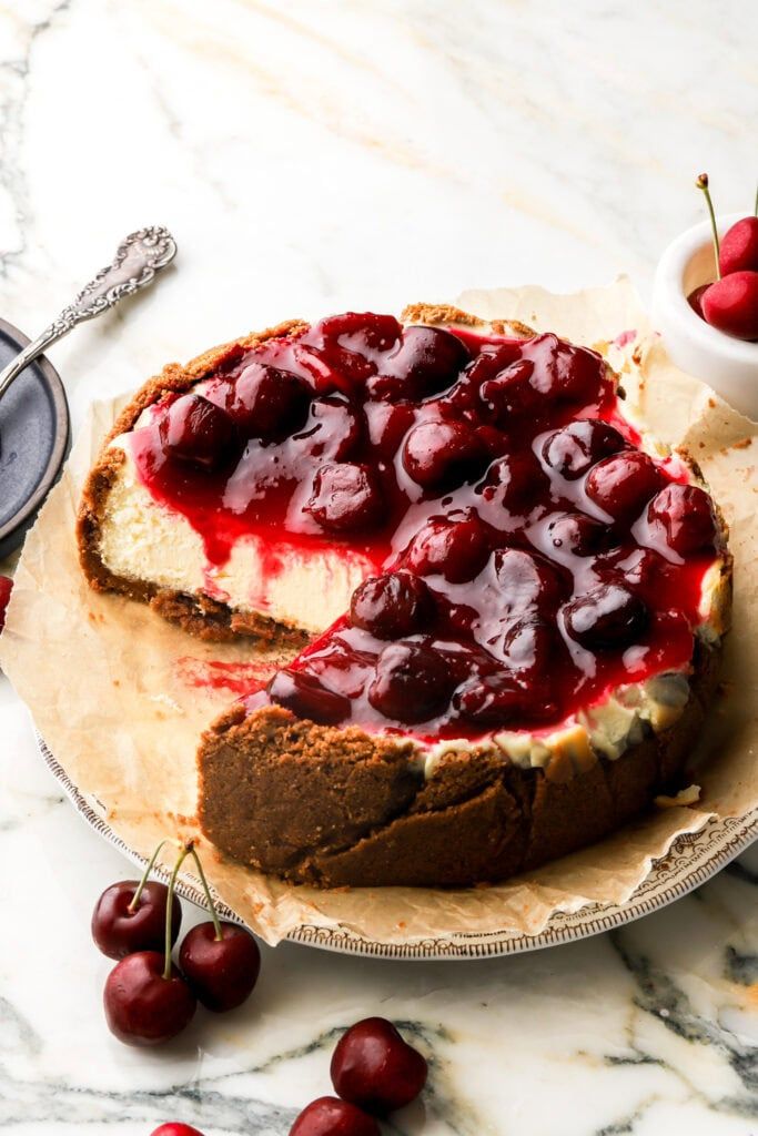 a cheesecake with cherries on top is sitting on a plate next to some cherries