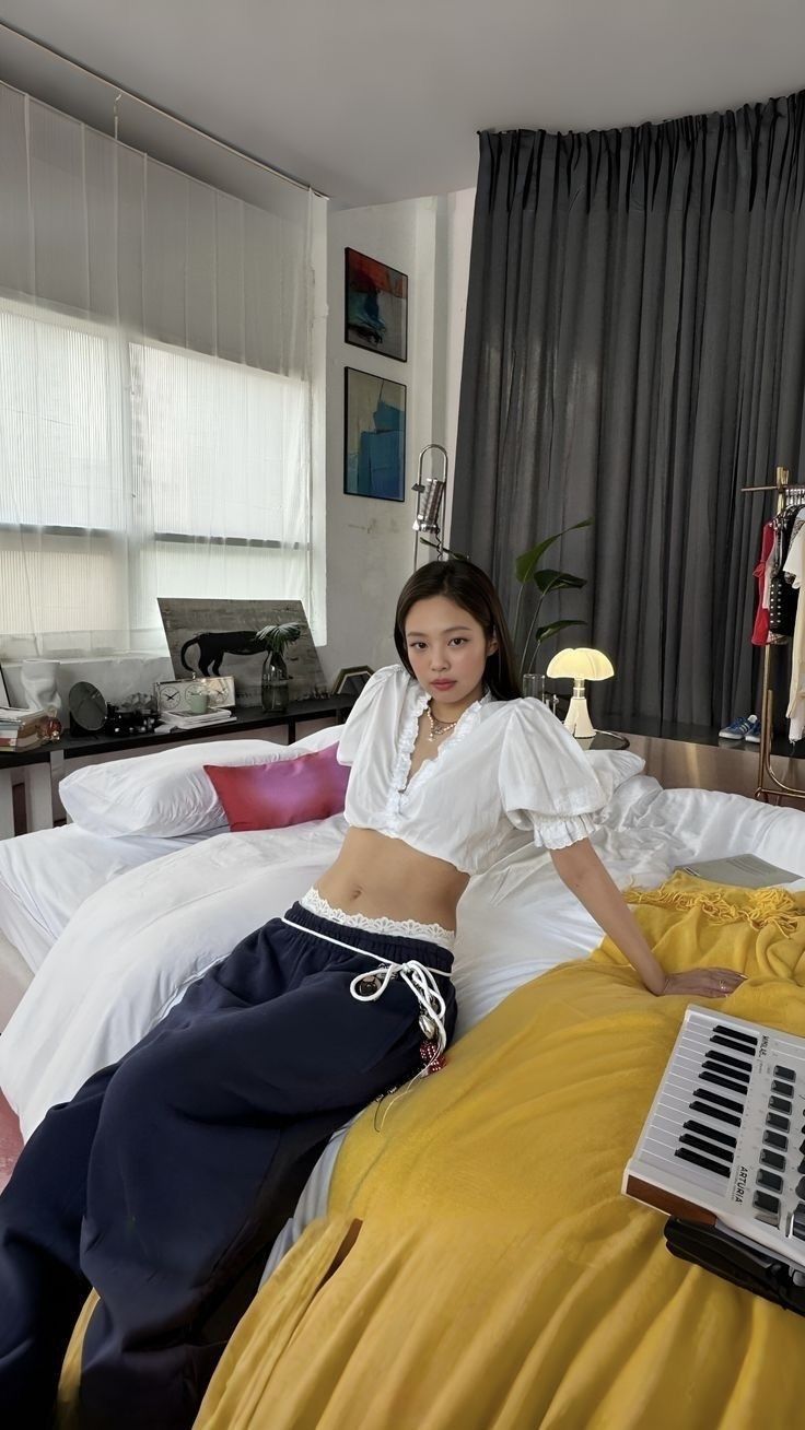 a woman sitting on top of a bed next to a yellow comforter in a bedroom