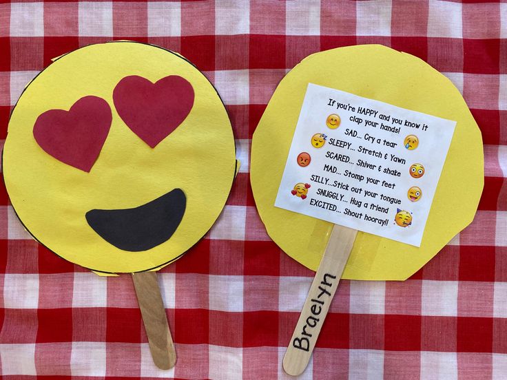 two paper fans with hearts on them sitting on a red and white checkered tablecloth