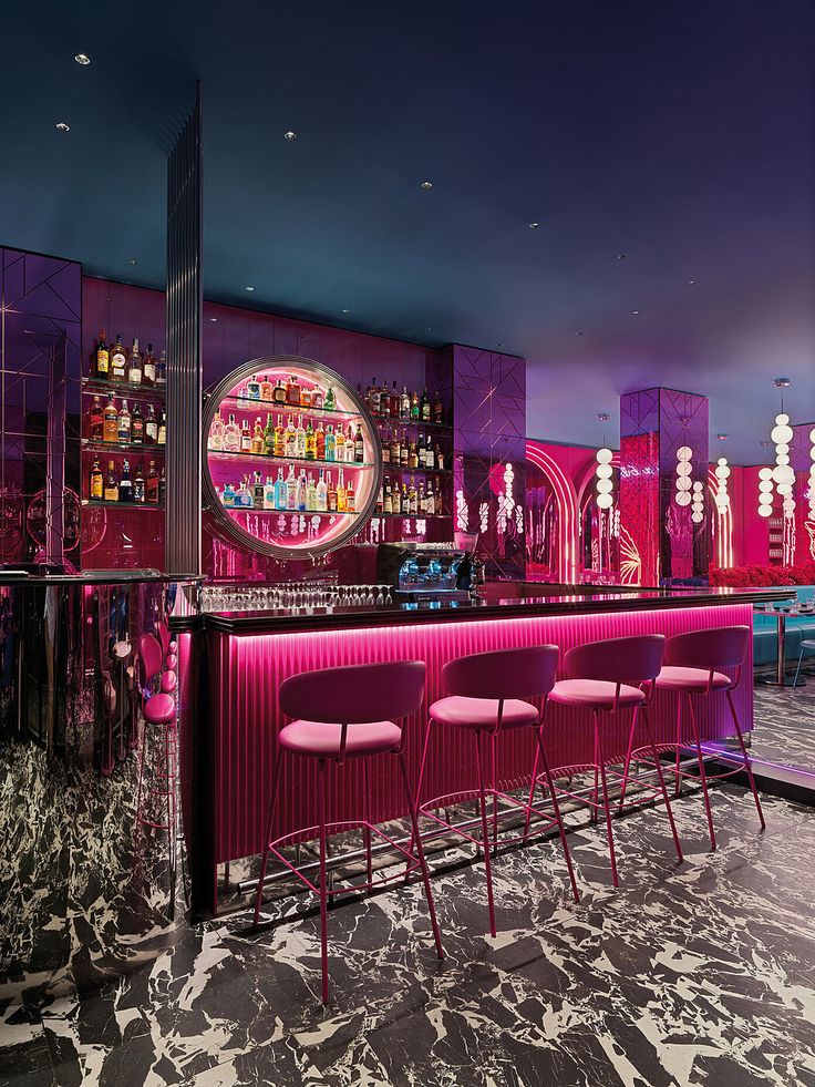 a bar with pink chairs and neon lights